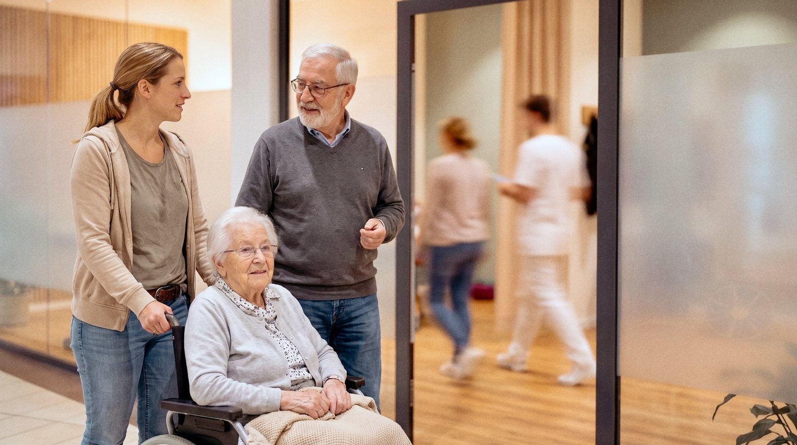 Eine Frau schiebt eine ältere Dame im Rollstuhl durch die Mall des Porcia MedCenter in Spittal an der Drau, ein Mann geht daneben
